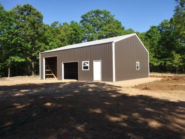 A brown Lucky pole barn with white trim, two door openings and a walk door