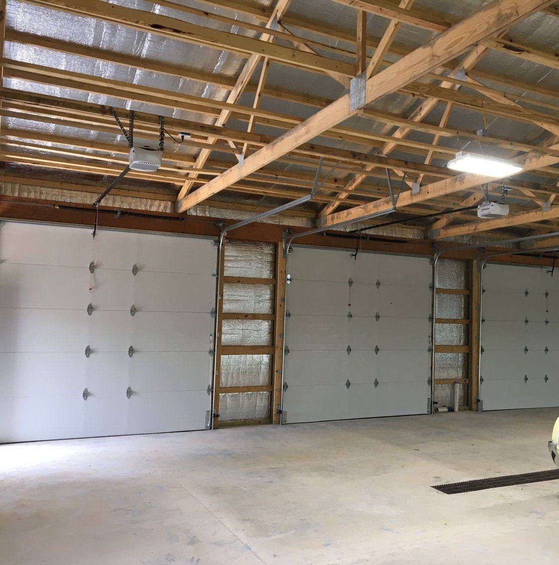 Inside a Lucky pole barn: trusses overhead and three overhead doors